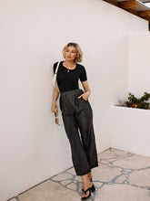 A lady wears a knit top and leather pants.